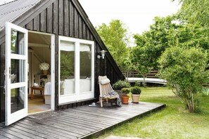 A wooden cabin with a deck, a chair, and potted plants. - Close to beach, forest and bike trails (Grenå)