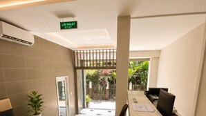 A reception area with a marble floor, a reception desk, a sofa, and potted plants. - Hua Yi Hotel - Pham Ngu Lao  (Ho Chi Minh City)