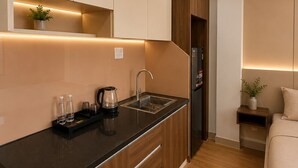 A modern kitchen with wooden cabinets, a black countertop, and a built-in oven. - Hua Yi Hotel - Pham Ngu Lao  (Ho Chi Minh City)