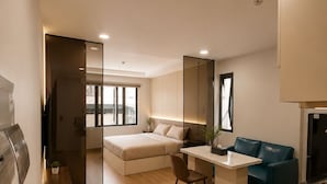 A modern apartment with a bed, a desk, a sofa, and a kitchen area. - Hua Yi Hotel - Pham Ngu Lao  (Ho Chi Minh City)
