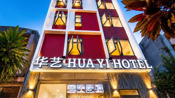 A hotel with a modern facade, a prominent entrance, and a sign displaying the name 'HUAYI HOTEL'. - Hua Yi Hotel - Pham Ngu Lao  (Ho Chi Minh City)