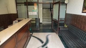A reception area with a reception desk, a sofa, a staircase, and a clock on the wall. - Hotel Bella Vista (Jaipur)