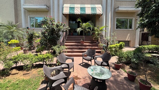 A building with a covered entrance, outdoor seating, and potted plants. - Hotel Bella Vista (Jaipur)