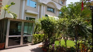 A building with large windows, a glass entrance, and a well-maintained garden with various plants. - Hotel Bella Vista (Jaipur)
