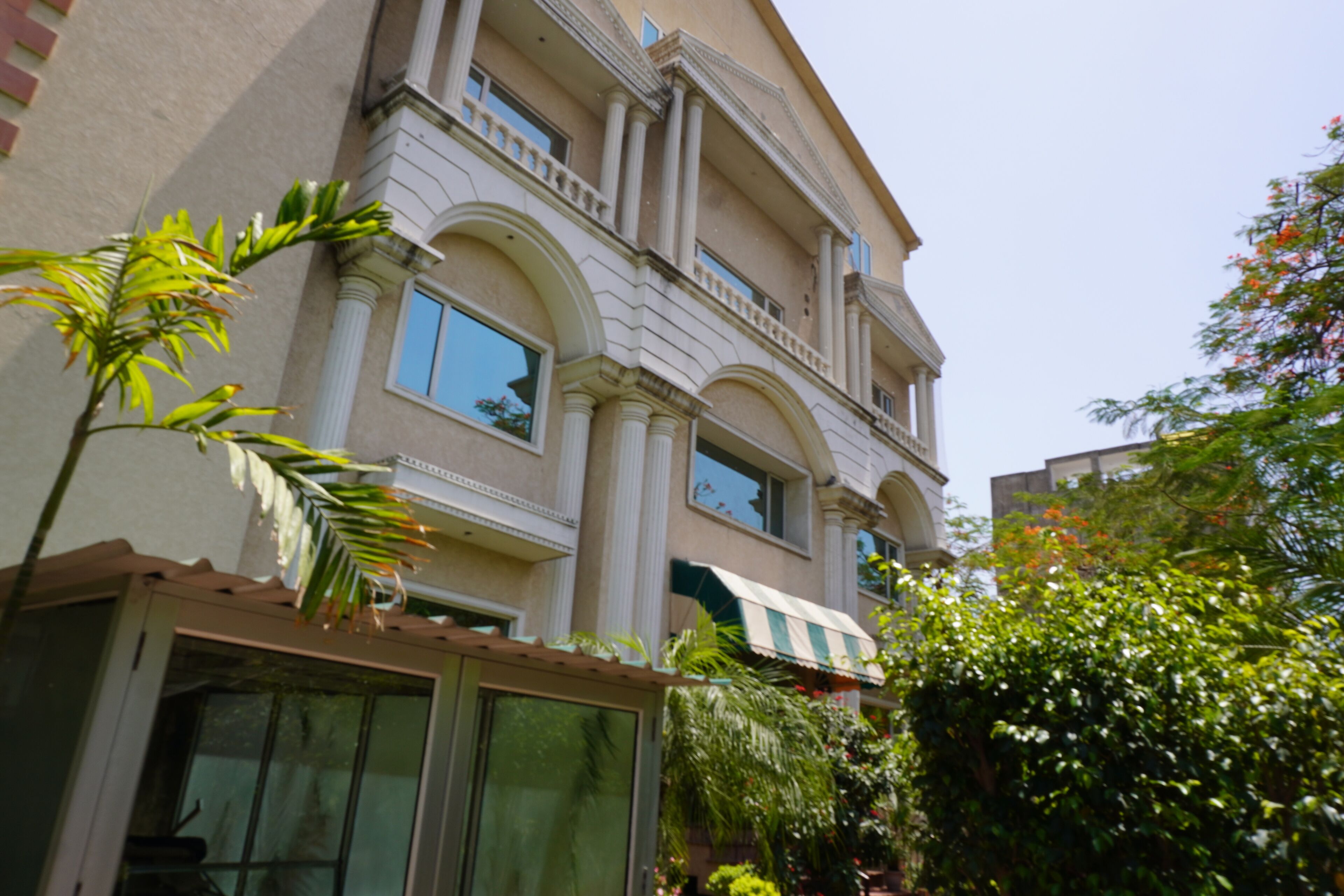 Un immeuble à plusieurs étages doté de grandes fenêtres, d’un balcon et d’une entrée abritée.