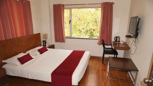 A hotel room with a bed, a desk, a chair, a television, and a window with curtains. - Hotel Bella Vista (Jaipur)
