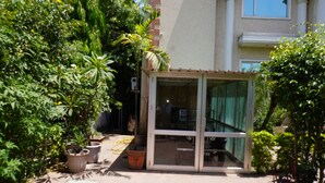 A courtyard with potted plants, a glass door entrance, and a building with columns. - Hotel Bella Vista (Jaipur)
