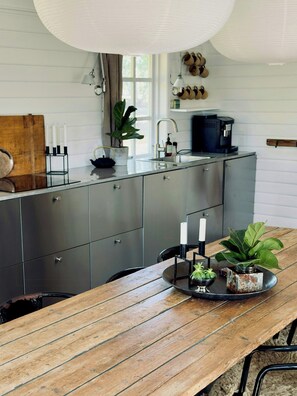 Eine moderne Küche mit Holztisch, Kaffeemaschine und einem Blumentopf.