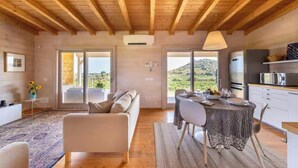 A modern interior with a wooden ceiling, a sofa, a dining table with chairs, and a kitchen area. - House with pool and citrus grove near Noto (Noto)