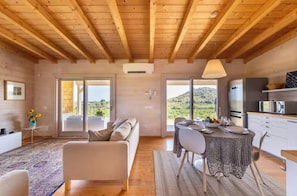A modern interior with a wooden ceiling, a sofa, a dining table with chairs, and a kitchen area. - House with pool and citrus grove near Noto (Noto)