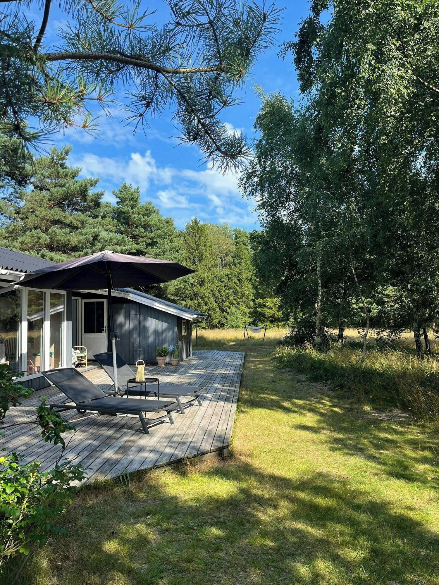 Et hus med terrasse, udendørs møbler og hængekøje.