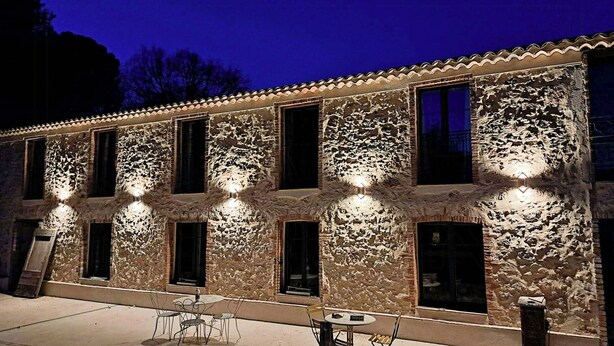 A building with multiple windows and a patio area with tables and chairs. - Unique gite in a renovated factory in Provence (Salernes)