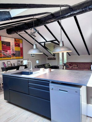 A modern kitchen with a central island, pendant lighting, and exposed beams.