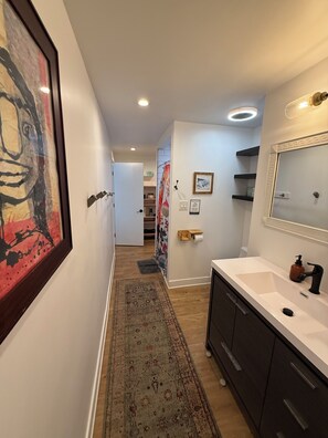 A hallway with a patterned rug, a white sink with a mirror, and a framed artwork on the wall. - Charming hwood Hills 2-bdroom guesthouse totally privte.big Bckyard, jacuze etc (Los Angeles)