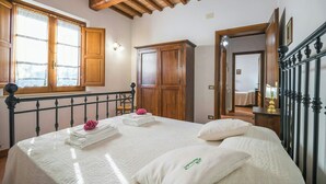 Quarto com cama, guarda-roupa de madeira e janela com cortinas.