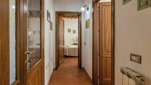 Um corredor com portas de madeira, um radiador e quadros nas paredes.