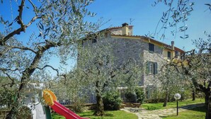 Un edificio de piedra con un sendero de jardín que lleva a un parque infantil con un tobogán.