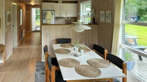 Een eetgedeelte met een houten tafel, stoelen en uitzicht op de omgeving.