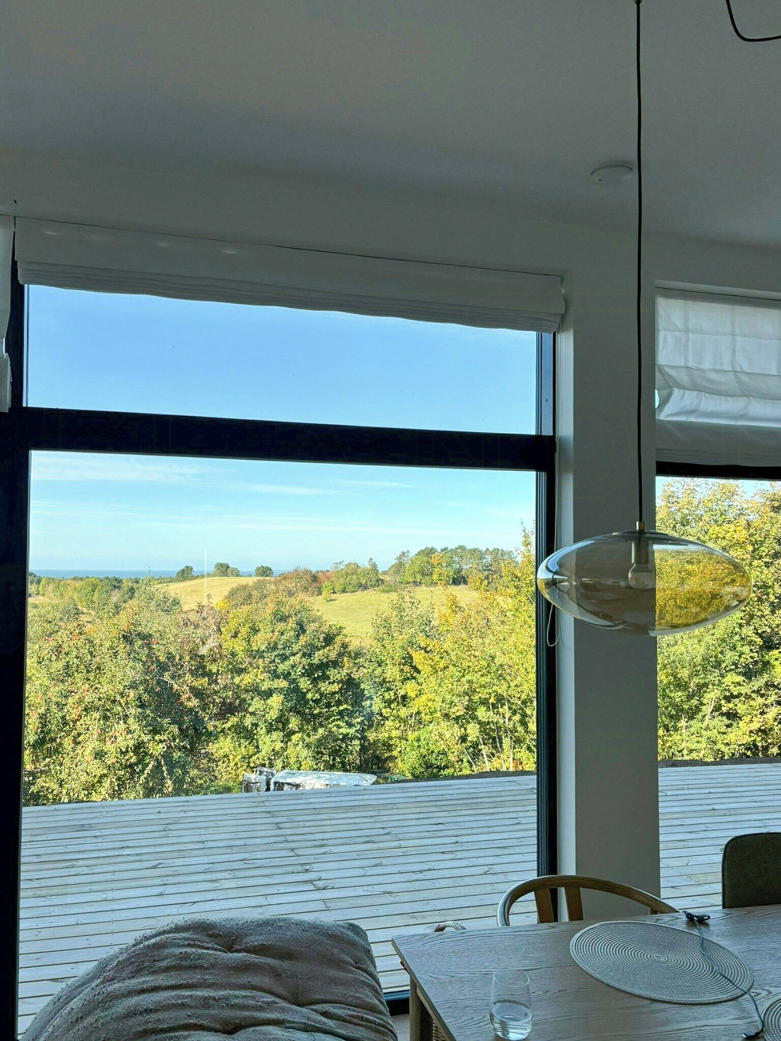 A room with a large window, a dining table, and a chair.