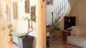 Ein Wohnzimmer mit einer Couch, einer Topfpflanze, einer Holzsäule und einer Treppe.