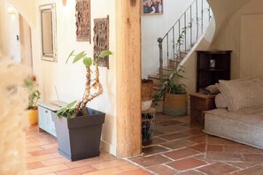 A living room with a sofa, a potted plant, a wooden column, and a staircase. - Provençal farmhouse in preserved natural setting (Fréjus)
