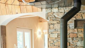 Ein gemütliches Wohnzimmer mit Steinwand, Kamin, einer Couch und einer Vase mit Pampasgras.