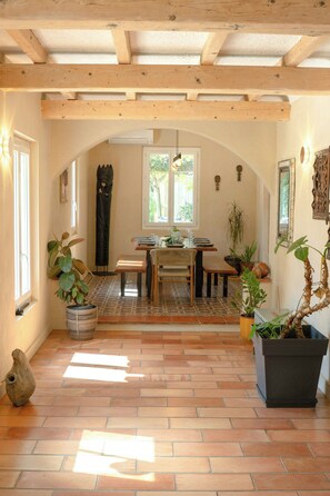 A dining area with a wooden ceiling, a tiled floor, and a table with chairs. - Provençal farmhouse in preserved natural setting (Fréjus)