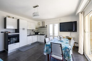 A modern kitchen with white cabinets, a built-in oven, and a dining area with a table set for two. - Spacious villa with sea views (Cipressa)