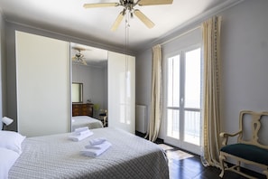 Ein Hotelzimmer mit Bett, einem Sessel, einem großen Spiegel und einem Deckenventilator.