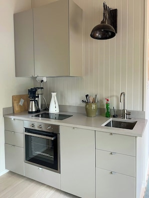 A modern kitchen with a built-in oven, a double sink, and a coffee maker. - Modern cabin in the heart of Småland (Tolg)