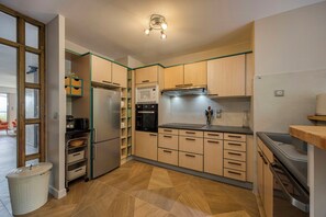 Eine moderne Küche mit Holzausbau, einem Edelstahl-Kühlschrank, einer Mikrowelle und einem Spülbecken.