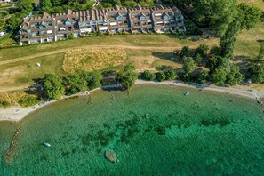 Ein Luftbild eines Küstenhotels mit mehreren Gebäuden, einem Strand und klarem Wasser.