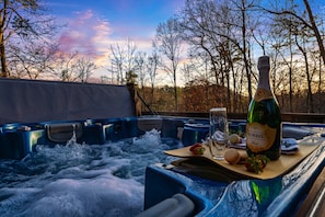 A hot tub with a bottle of Korbel wine, a glass, and snacks. - Rustic Cove - Hot Tub, Game Room, Dog Friendly (Pigeon Forge)