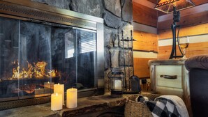 Ein gemütlicher Kamin mit Steinwand, Glaseinsatz und Kerzen.