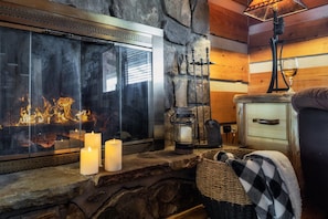 A cozy fireplace with a stone wall, a glass screen, and candles. - Rustic Cove - Hot Tub, Game Room, Dog Friendly (Pigeon Forge)