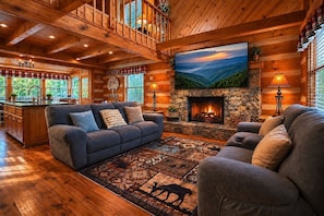 A log cabin interior with a fireplace, a large TV, and a cozy seating area. - Rustic Cove - Hot Tub, Game Room, Dog Friendly (Pigeon Forge)