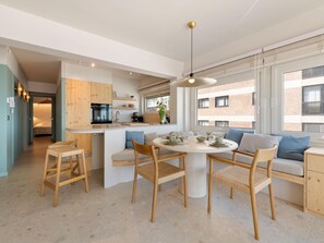 Ett modernt kök med en central köksö, trästolar och ett matbord med plats för fyra personer.