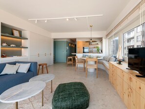 A modern living space with a sofa, a dining area, and a kitchen. - Sunny corner apartment with luxury sea view. (Blankenberge)