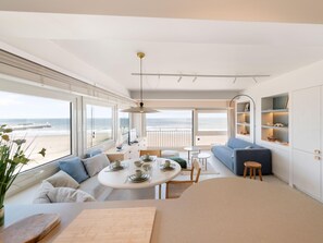 A modern interior with a dining area, sofa, and a view of the sea. - Sunny corner apartment with luxury sea view. (Blankenberge)