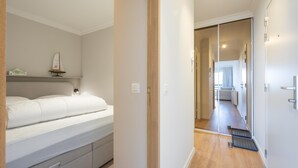 Een slaapkamer met een bed, nachtkastje en een klein plankje met een decoratief object.