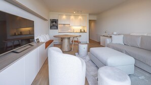 Een moderne woonkamer met een bank, voetenbankje en een eethoek met een tafel en stoelen.