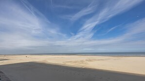 Een strand met een heldere lucht en voetafdrukken in het zand.