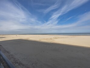 Ein Strand mit blauem Himmel und Fußabdrücken im Sand.