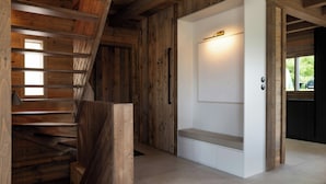 Un interior de madera con una escalera, una puerta blanca y un banco.