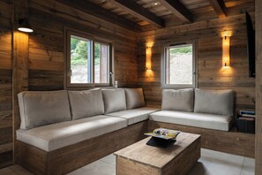 A wooden interior with a sectional sofa, two windows, and a table with a magazine. - Family chalet with Vosges mountain views in Gérardmer (Gérardmer)