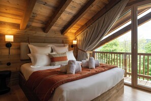 A wooden cabin bedroom with a large bed, headboard, bedside lamps, and a balcony with a view. - Family chalet with Vosges mountain views in Gérardmer (Gérardmer)