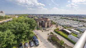 Un quartier résidentiel avec un grand immeuble, des voitures garées et un ciel dégagé.