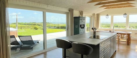 A spacious kitchen with a large island, bar stools, and a view of the outdoors.