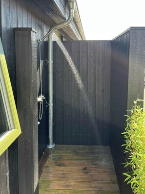 A wooden deck leading to a dark wooden shower enclosure with a metal pipe. - Summer house with wilderness bath and water views (Vinderup)