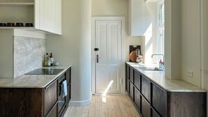 A modern kitchen with a central island, dark wood cabinetry, and a light wooden floor.
